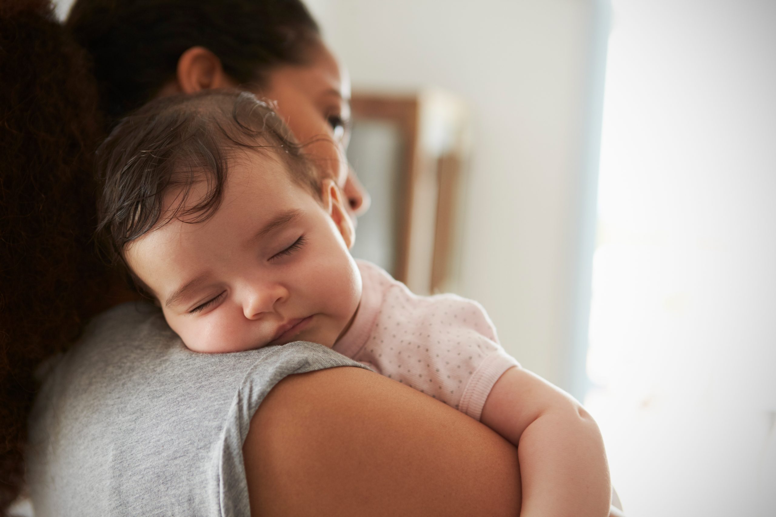 Mazuļa miegs. Mamma tur rokās guļošu mazuli